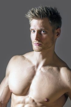 Portrait of a muscle sport man with blue eyes, blond hair and strong pectoral muscles