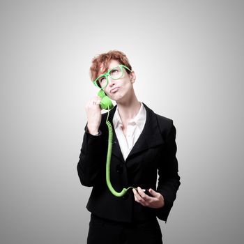 doubtful business woman with green phone on gray background