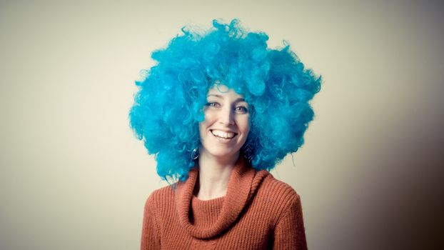 beautiful girl with curly blue wig and turtleneck on white background