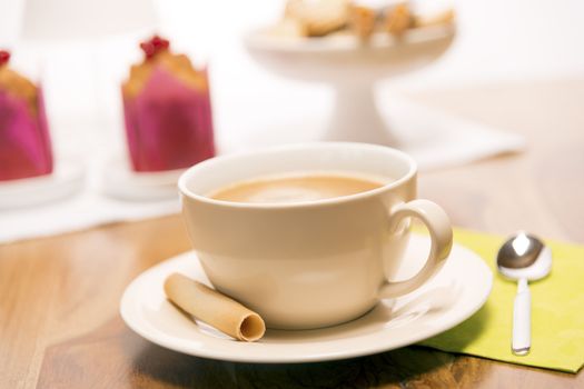 Cup of coffee with spoon, cookies on wooden table