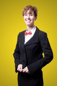 smiling elegant businesswoman with bow tie on yellow background