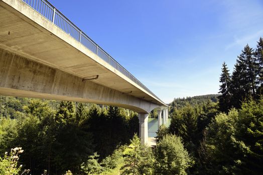 Concrete-Bridge over the river called "Lech". Placed in Germany, Bavaria, Allgäu. There are also coniferous trees and blue sky, sunny weather.