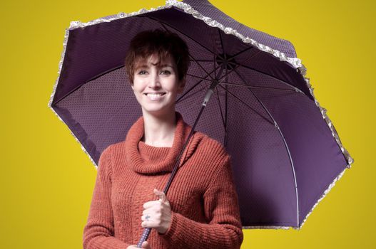 beautiful woman with sweater and umbrella on yellow background