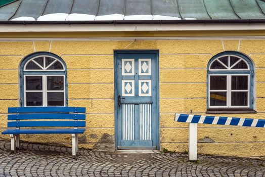 Yellow house with blue bench and paved street in the town Dachau in Germany in winter