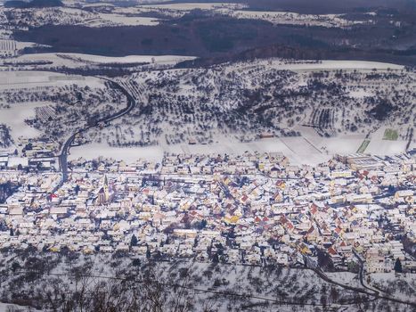 Village in winter landscape with snowed fields, trees, houses, forest