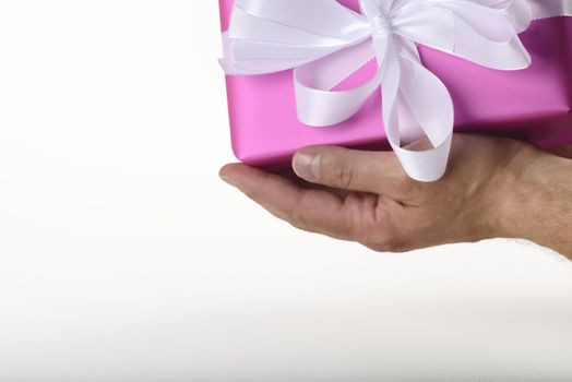 gift with white ribbon in purple paper on white underground holding in hand