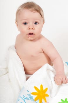 Little boy in white blanket with flowers in studio