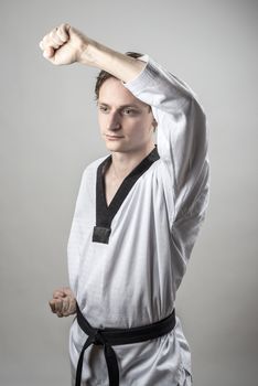 Taekwon-Do champoin on a grey background doing a defense block