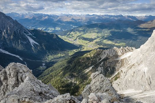 Wild landscape in South Tyrol with view to a village, forest, meadows, alps on a sunny day with blue sky and clouds