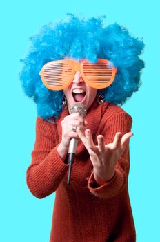 beautiful girl with curly blue wig and turtleneck on blue background