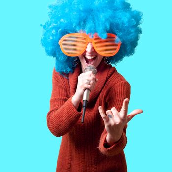beautiful girl with curly blue wig and turtleneck on blue background