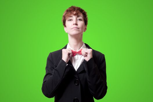 elegant businesswoman adjusting bow tie on green background