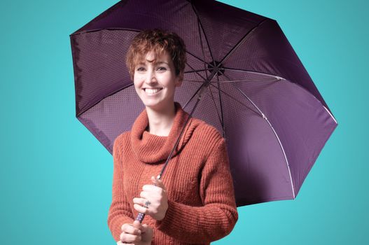 beautiful woman with sweater and umbrella on blue background