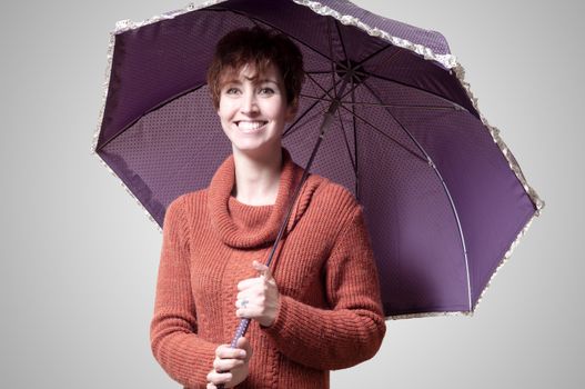 beautiful woman with sweater and umbrella on gray background