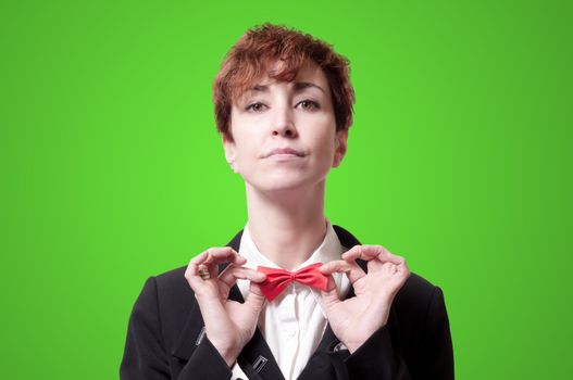 elegant businesswoman adjusting bow tie on green background