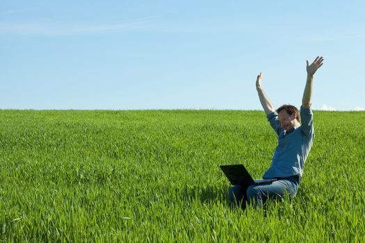 young man using laptop in the field