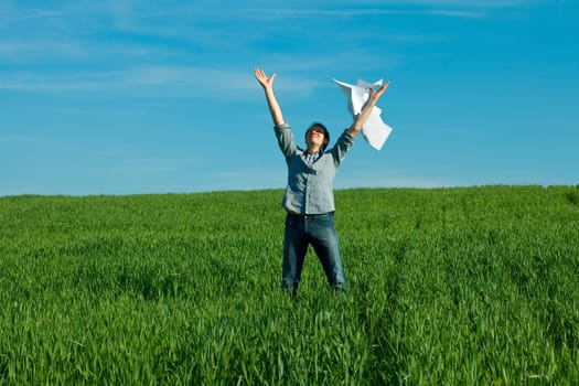 young man throwing a paper in the green field