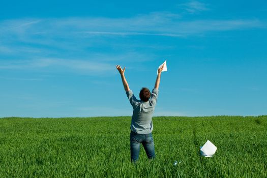 young man throwing a paper in the green field