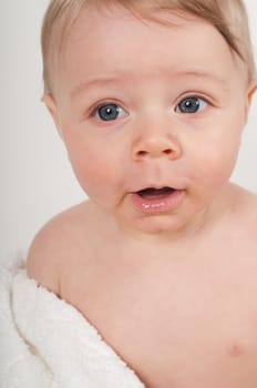 Happy little boy in white blanket in studio