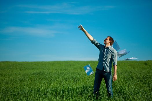 young man throwing a paper in the green field