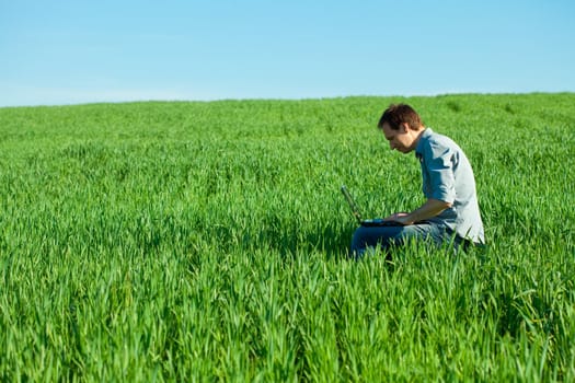 young man using laptop in the field