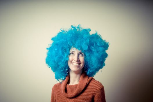 beautiful girl with curly blue wig and turtleneck on white background