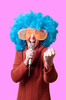 beautiful girl with curly blue wig and turtleneck on pink background