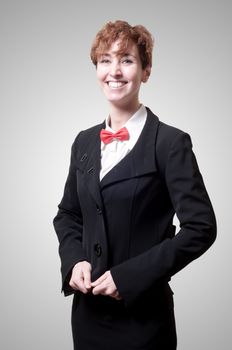 smiling elegant businesswoman with bow tie on gray background