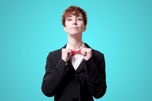 elegant businesswoman adjusting bow tie on blue background