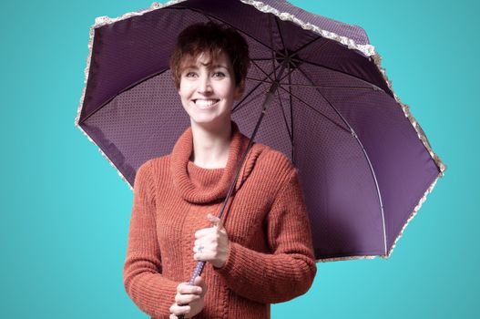 beautiful woman with sweater and umbrella on blue background