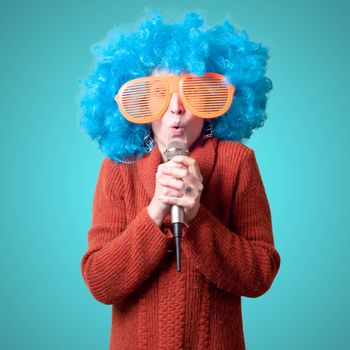 beautiful girl with curly blue wig and turtleneck on blue background