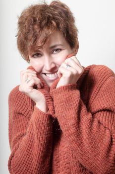 smiling short hair girl cold with orange sweater on white background