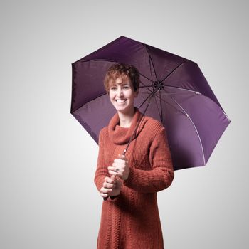 beautiful woman with sweater and umbrella on gray background