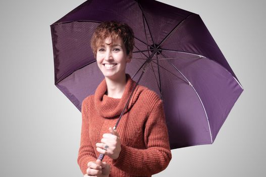 beautiful woman with sweater and umbrella on gray background