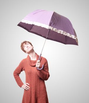 beautiful woman with sweater and umbrella on gray background