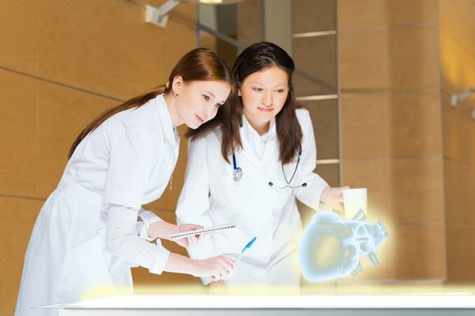 two doctors stand near glowing table discussing. projected objects on a desk