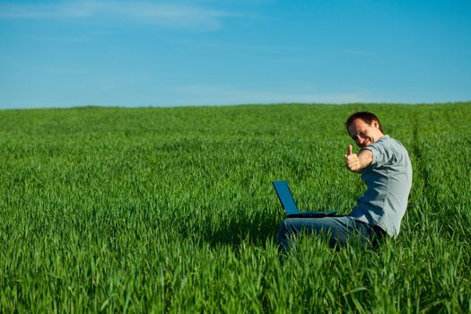 young man using laptop in the field