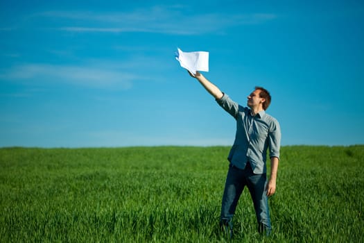 young man throwing a paper in the green field