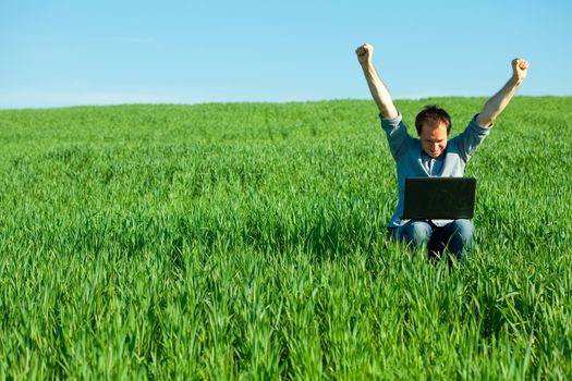 young man using laptop in the field