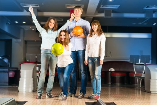 Group of young friends playing bowling, spending time with friends