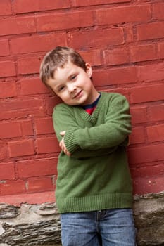 Cute little boy standing in front of a brick wall