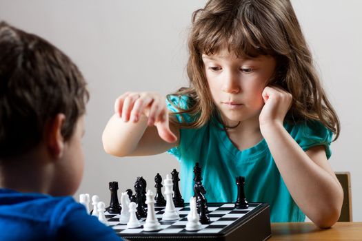 Cute little girl and boy playing chess together