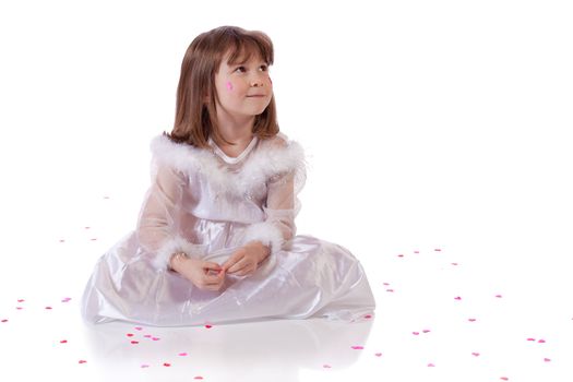 Cute little girl sitting on the floor with heart shaped confetti