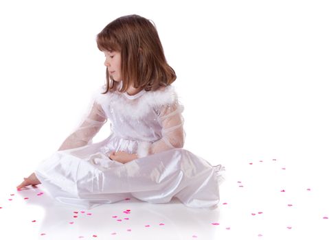 Cute little girl sitting on the floor with heart shaped confetti