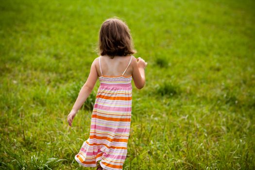 Cute little girl running in a grass field