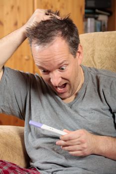 Surprised man holding a positive pregnancy test