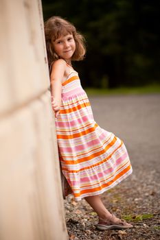 Little girl standing outside and leaning on a wall