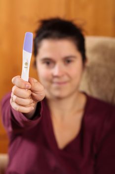 Happy woman holding a positive pregnancy test
