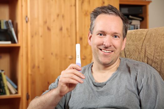 Happy man holding a positive pregnancy test