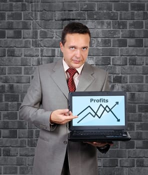 man with a laptop in hand points to chart of profits
